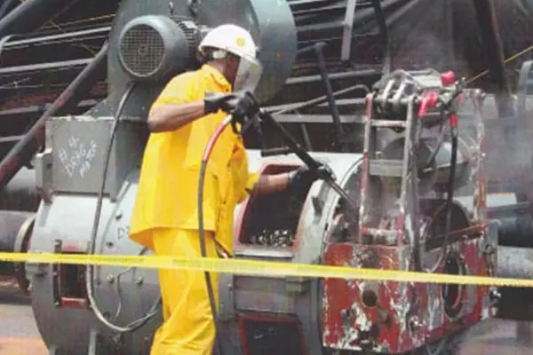 A man in yellow and white working on an engine.