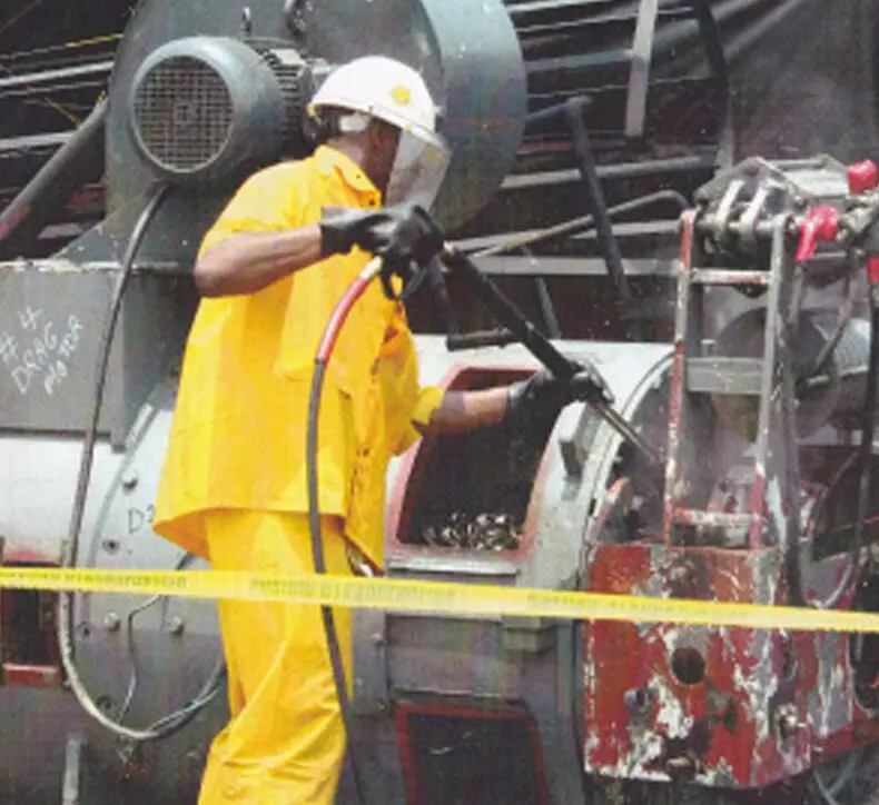 A man in a yellow jacket working on a machine with cleaning agents.
